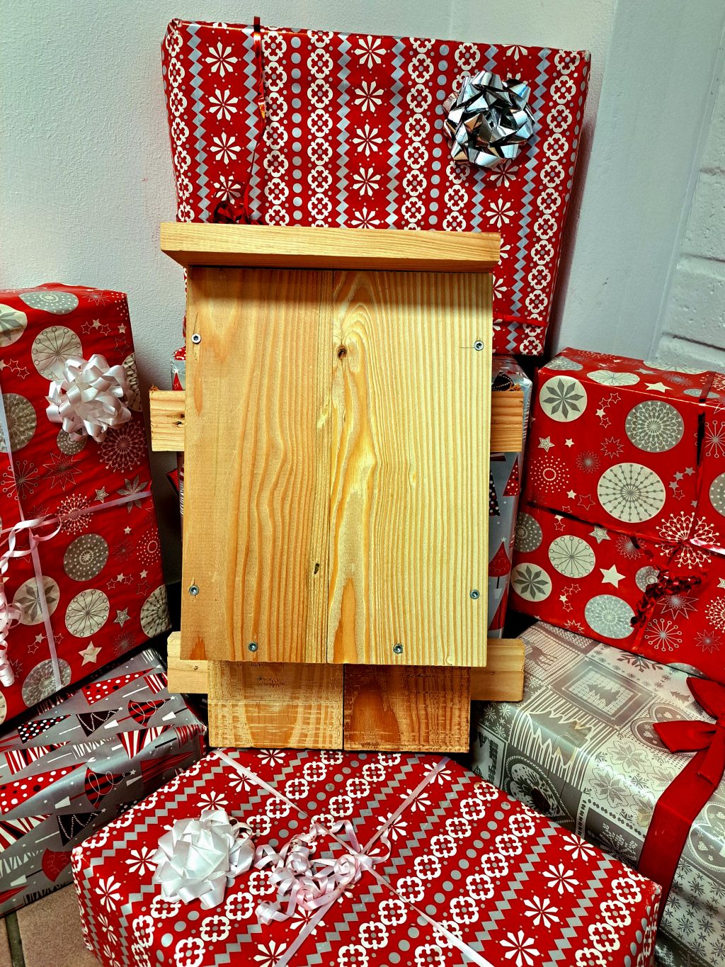 Een zelfgemaakte vleermuiskast tussen de in kerstpapier verpakte cadeautjes